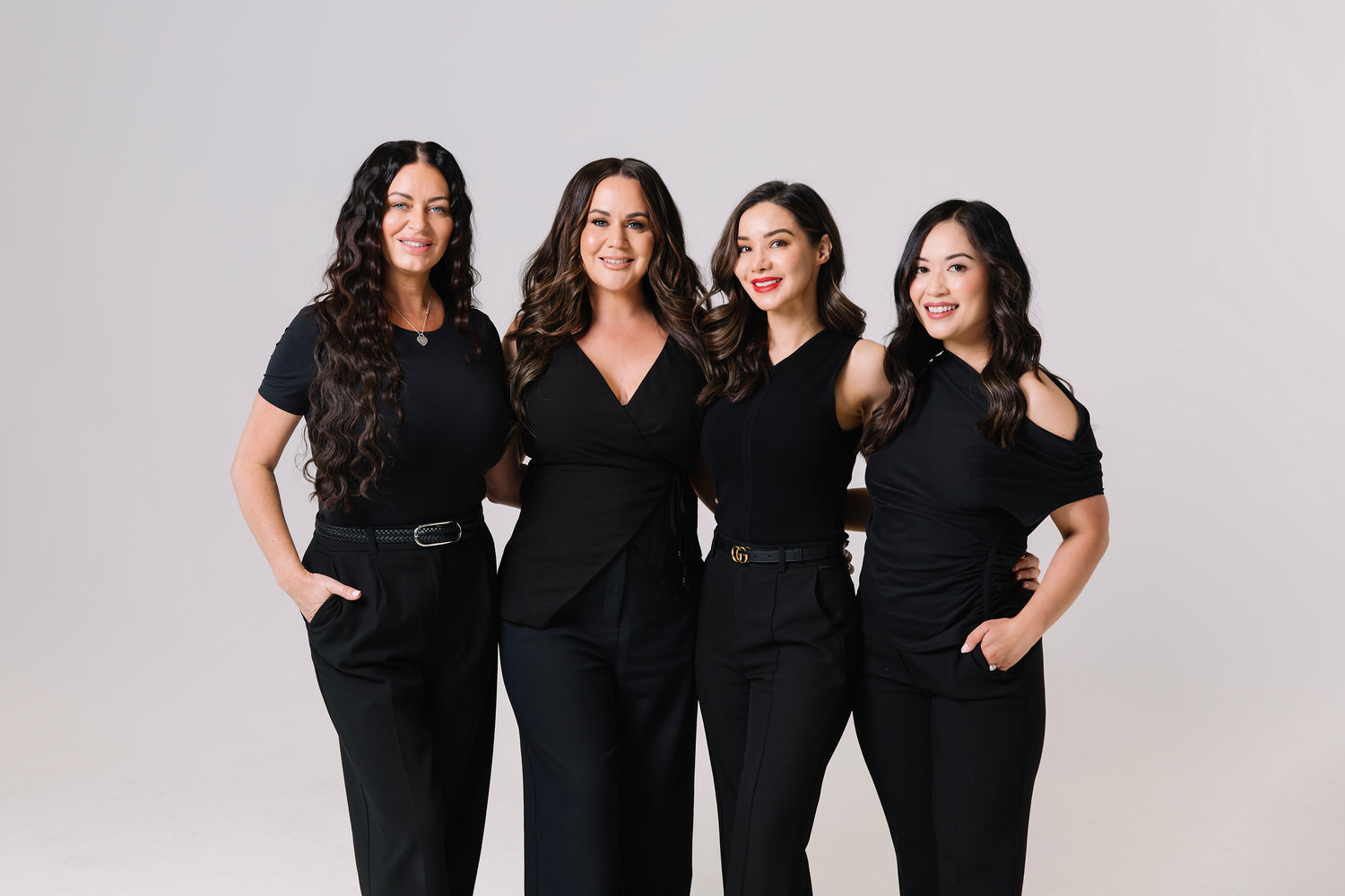 Four nurses in black outfits posing against a plain background